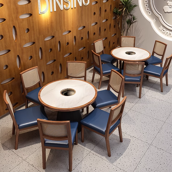 Dining room restaurant with round tables featuring marble tops and built-in BBQ holes.