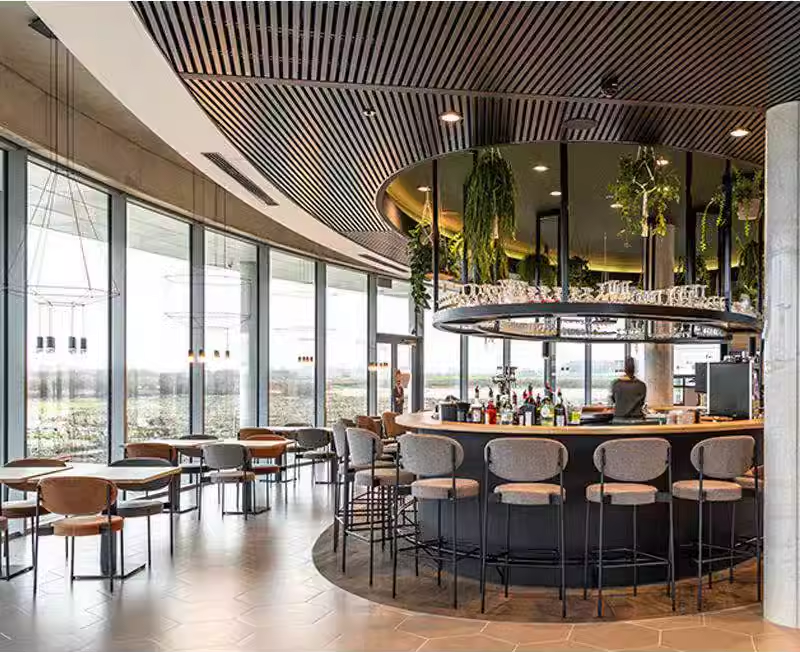 Elegant bar stools in neutral tones around a stylish minimalist bar counter with soft lighting and a clean design.