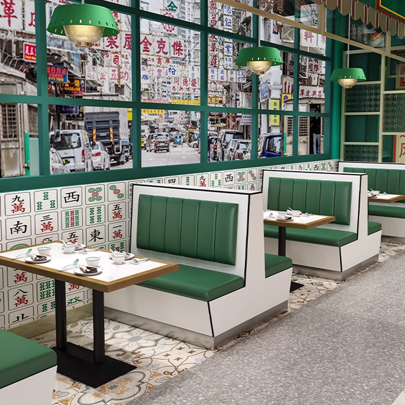 Dining area with green leather booths, rock slab dining tables, and vintage-style wall decor in a modern restaurant setting.