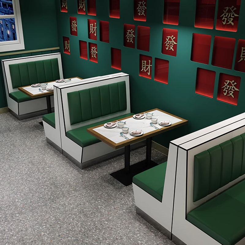 Rock slab dining tables paired with green leather booths in a stylish restaurant with vibrant decor and comfortable seating.