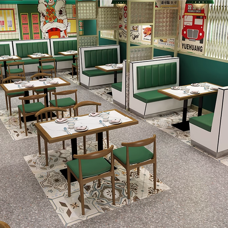 A dining area featuring green leather seating, rock slab dining tables, and patterned flooring, with a vibrant green wall decor.