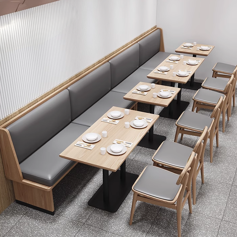 Modern dining setup featuring gray banquette seating paired with light wood dining chairs with gray cushioned seats.