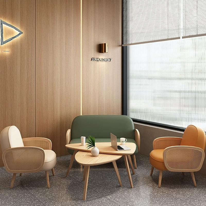 A modern café corner with a wooden table, chairs, and a green sofa, with natural light coming from the window.