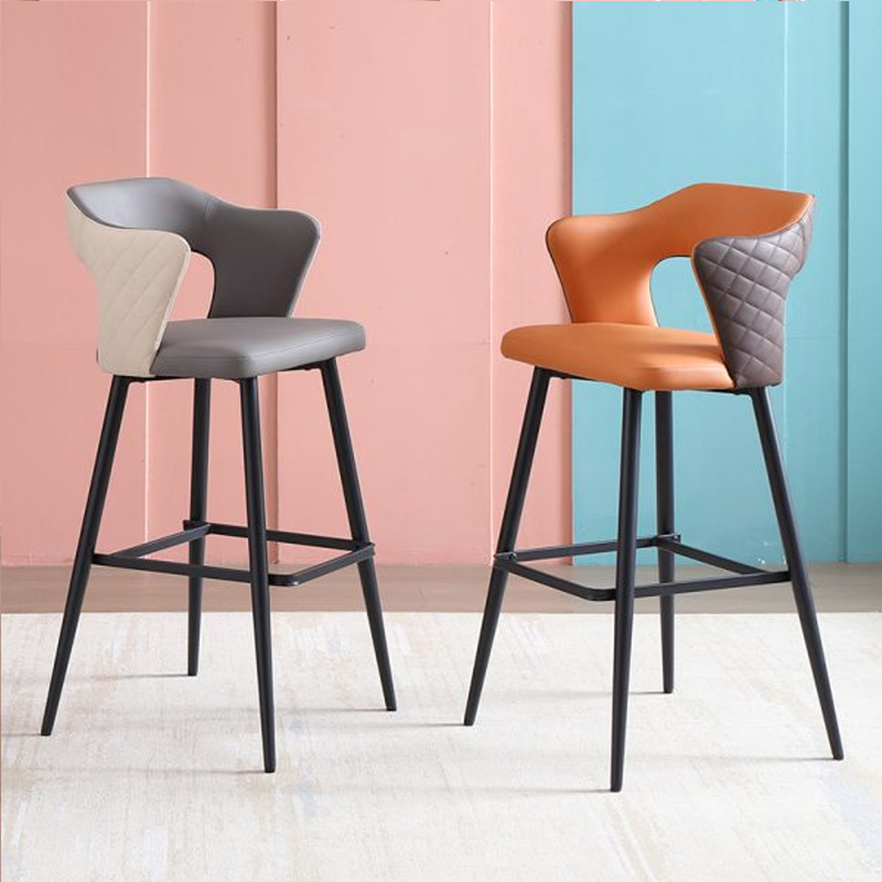 Two modern leather barstools in contrasting colors with quilted backrests and black metal legs.