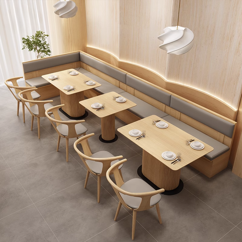 A modern dining space featuring a wooden rimmed rock slab dining table paired with wooden chairs in a light interior.