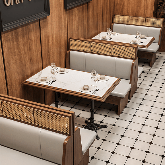 Modern restaurant dining area featuring cane-back booth seating with marble tables on a tiled floor.