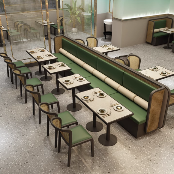 Modern restaurant dining area with cane-back chairs, green cushioned booths, and marble tables set for a meal.