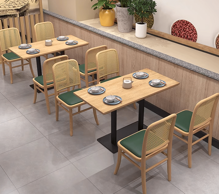 Modern restaurant seating with green cushioned chairs and light wood tables, clean and inviting interior decor.