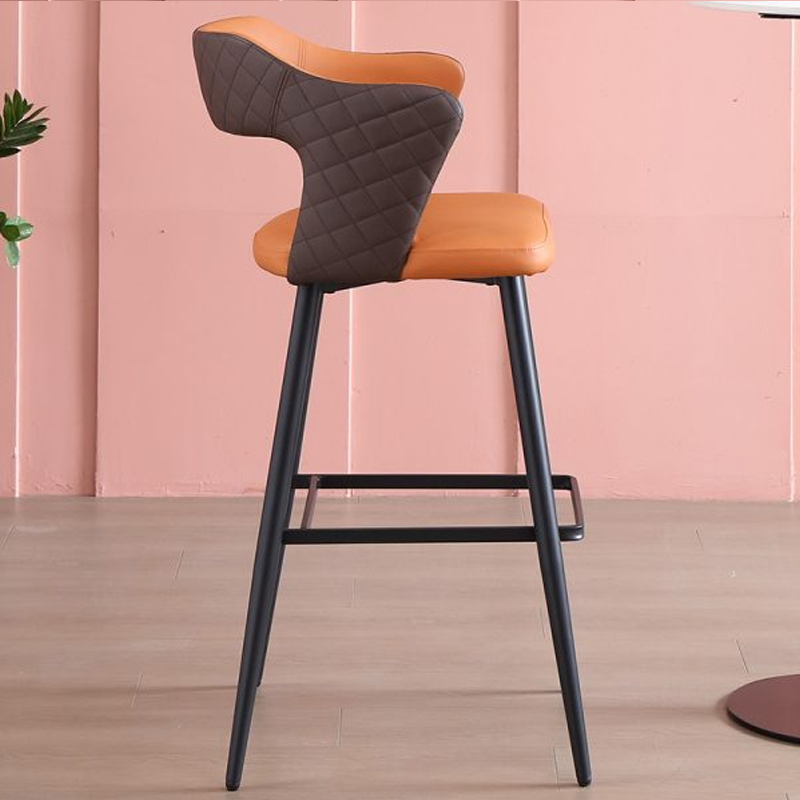 Side view of an orange leather barstool with black metal legs and quilted backrest.