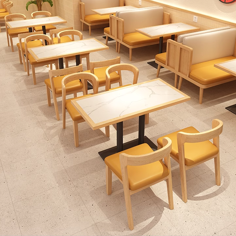 Cozy restaurant booths with yellow chairs and white marble tables.