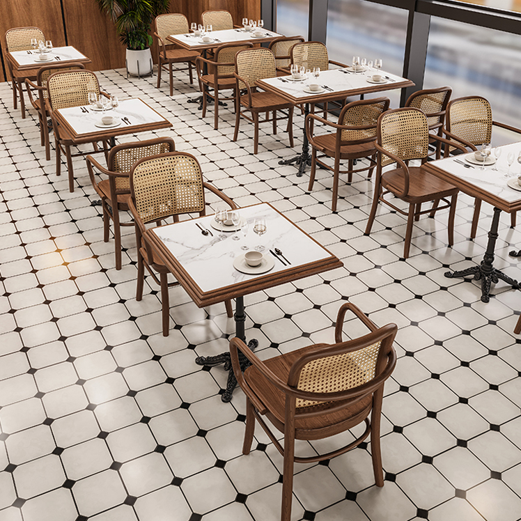 Restaurant dining area featuring wooden tables and cane-back chairs with a white and black tiled floor and marble table tops.