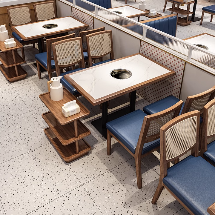 Restaurant interior with modern wooden tables and cane back chairs, blue leather seats, and an organized dining space.