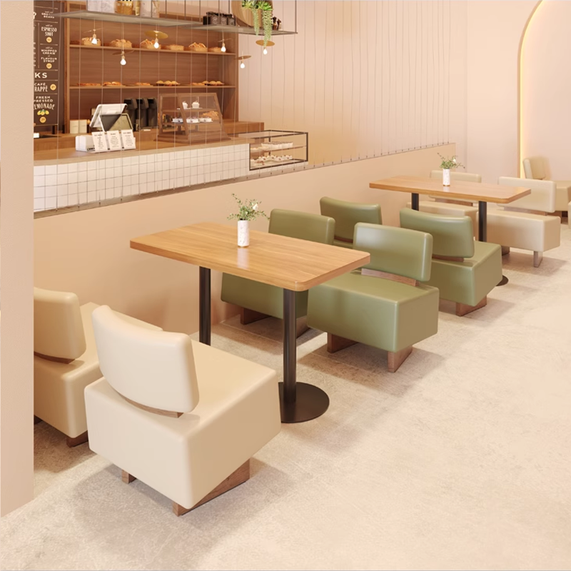 Cafe interior featuring light wooden tables and green seating. Simple design with a natural, inviting atmosphere.