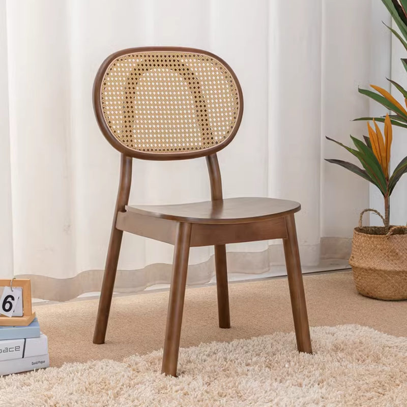 Wooden chair with cane backrest and smooth seat, placed near a potted plant in a light, airy room with a soft rug.