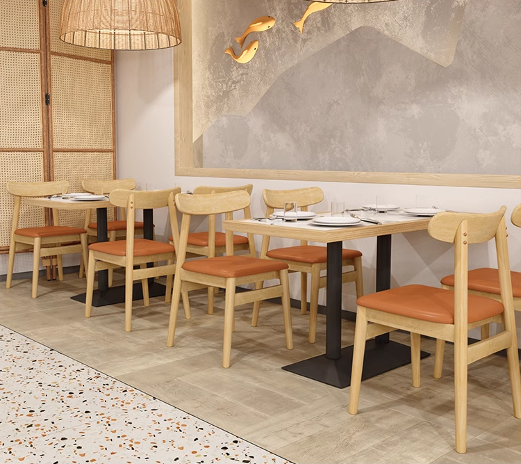 Cozy restaurant corner with wooden-edged rock slab dining tables and orange chairs, offering a stylish ambiance.