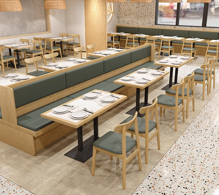 Restaurant dining area featuring wooden-edged rock slab dining tables with green seating.